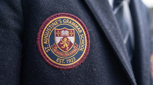 Detailed woven custom school crest badge stitched onto the left chest of a student school uniform shirt