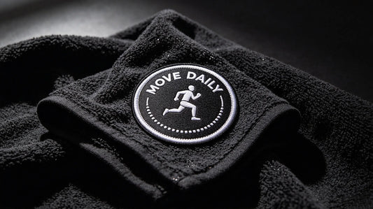 Close‑up of custom fitness studio 3D embroidered patch placed on black gym towel with subtle sweat texture