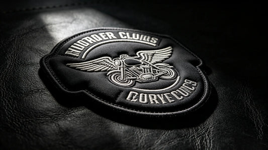 Low-angle dark studio shot of thick 3D raised embroidered motorcycle club crest patch, dramatic side lighting highlighting pronounced sculpted foam relief and layered stitching texture.