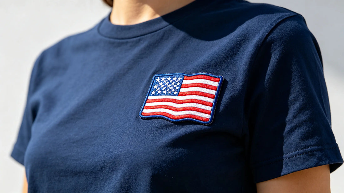 Close‑up of Fourth of July patriotic custom 3D embroidered patch sewn onto navy cotton T‑shirt, bright summer outdoor lighting