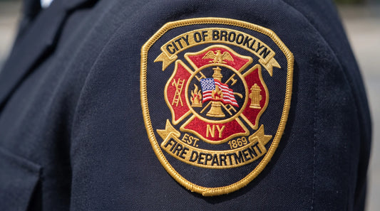 A professional woven Fire Department crest patch in crimson and gold, featuring a traditional firefighting symbol and an elegant merrowed border.